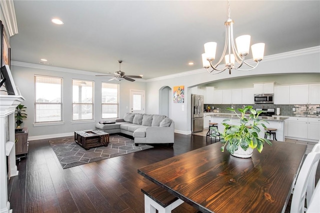 dining area featuring ceiling fan with notable chandelier, dark hardwood / wood-style flooring, and ornamental molding