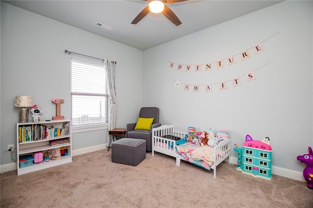 carpeted bedroom featuring ceiling fan and a nursery area