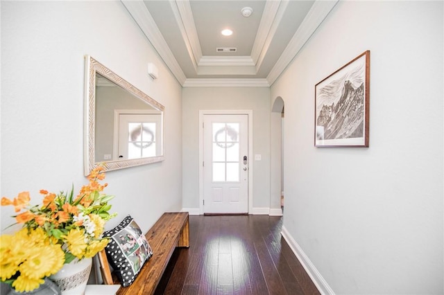 doorway with ornamental molding, dark wood-type flooring, and a raised ceiling