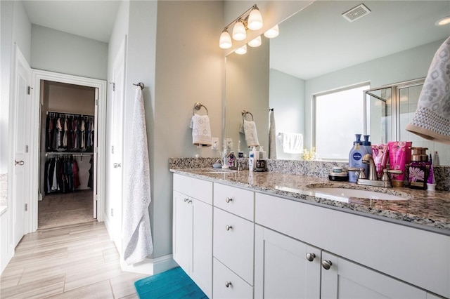 bathroom featuring a shower with door and vanity