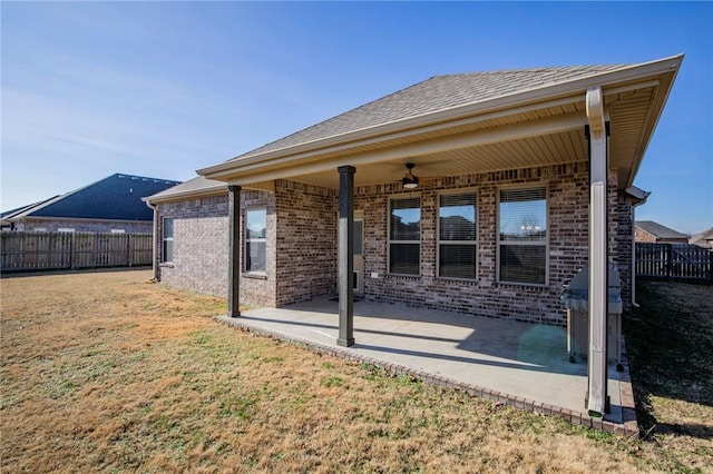 rear view of property featuring ceiling fan, a lawn, and a patio area