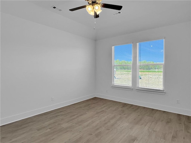 empty room featuring ceiling fan, light wood-type flooring, and vaulted ceiling