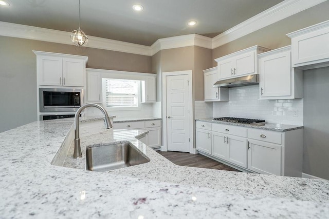 kitchen with sink, stainless steel appliances, light stone counters, decorative backsplash, and white cabinets