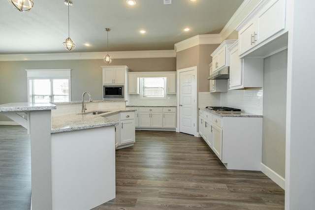 kitchen featuring kitchen peninsula, built in microwave, white cabinetry, and sink