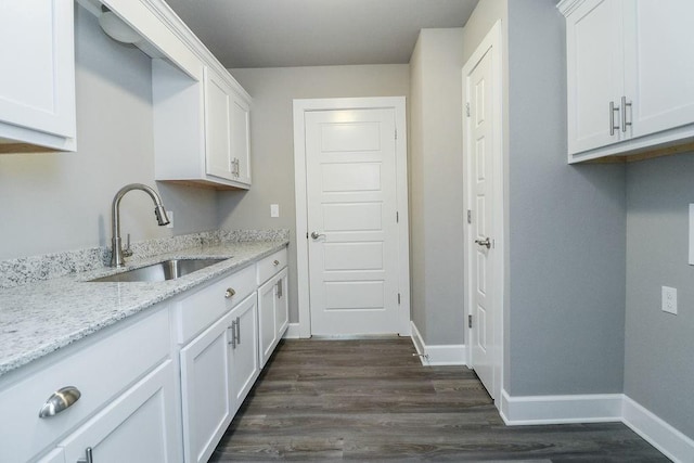 kitchen with light stone countertops, white cabinetry, sink, and dark wood-type flooring