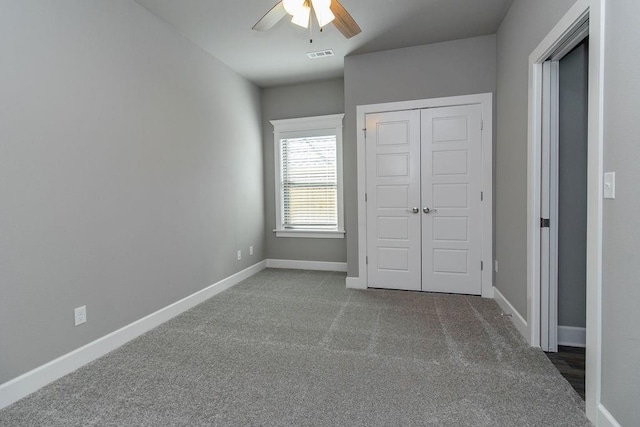 unfurnished bedroom with ceiling fan, a closet, and dark colored carpet