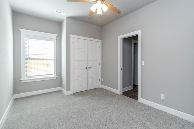 unfurnished bedroom featuring ceiling fan, a closet, and dark colored carpet