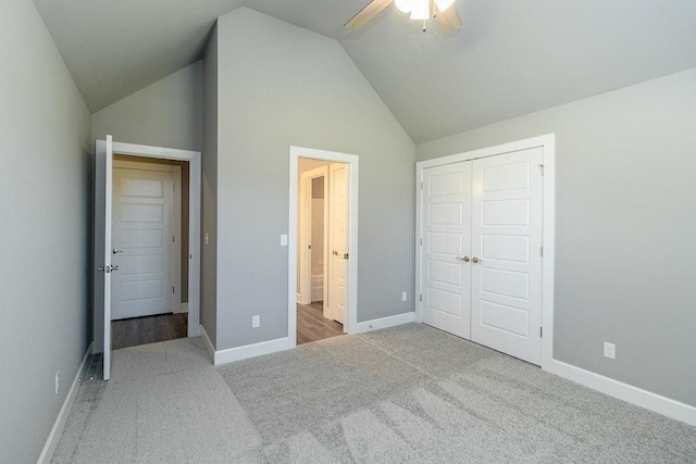 unfurnished bedroom featuring a closet, light colored carpet, high vaulted ceiling, and ceiling fan