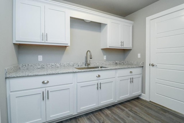 kitchen featuring white cabinets, dark hardwood / wood-style floors, light stone countertops, and sink