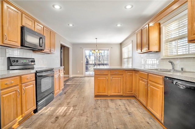 kitchen with a chandelier, a sink, light wood-style floors, a peninsula, and black appliances