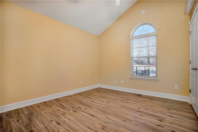 spare room featuring baseboards, vaulted ceiling, and wood finished floors