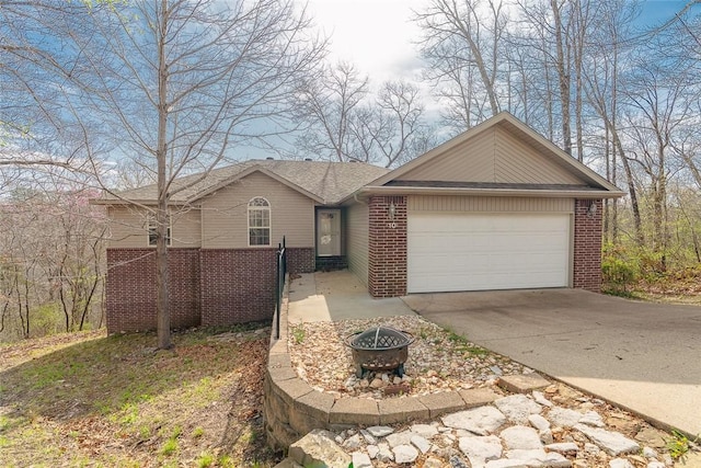 view of front of property featuring an attached garage, brick siding, a fire pit, and concrete driveway