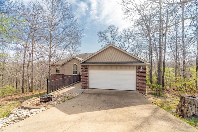 exterior space featuring fence, driveway, an attached garage, and brick siding