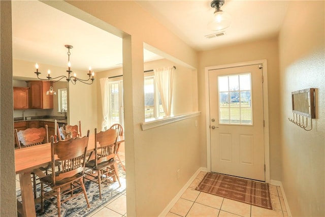 doorway to outside with light tile patterned floors, visible vents, and baseboards