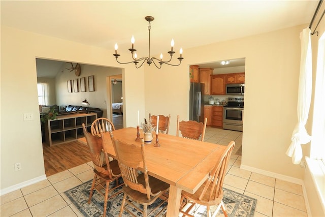 dining space featuring light tile patterned floors, baseboards, and a notable chandelier