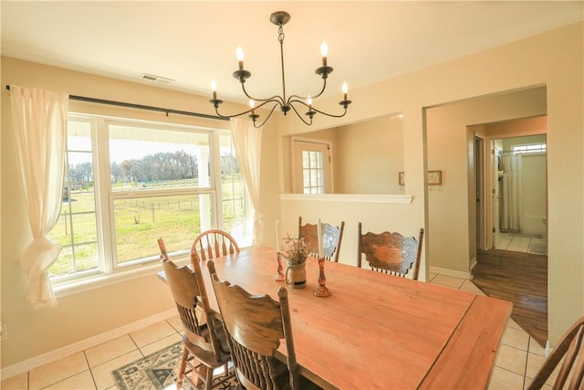 dining room with light tile patterned floors, baseboards, visible vents, and an inviting chandelier