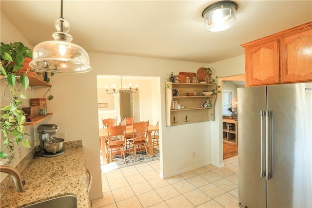 kitchen with open shelves, light tile patterned flooring, high quality fridge, a sink, and light stone countertops