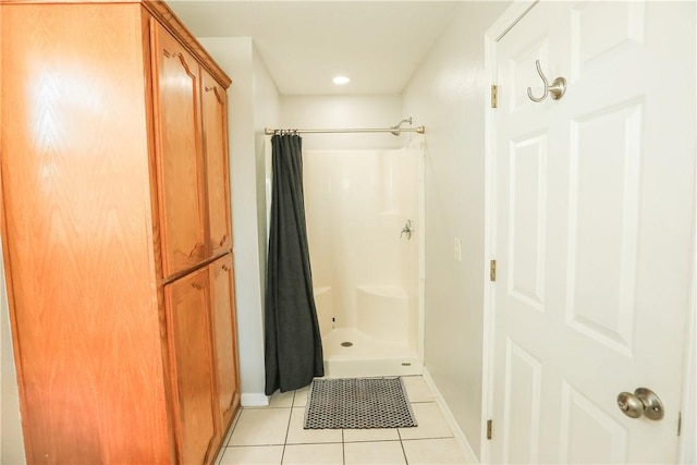 bathroom with a stall shower, tile patterned flooring, and baseboards