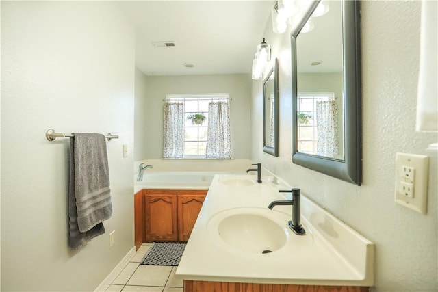 bathroom with a garden tub, visible vents, a sink, and tile patterned floors