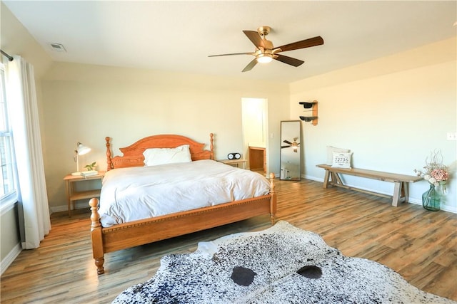 bedroom with hardwood / wood-style floors, ceiling fan, and multiple windows