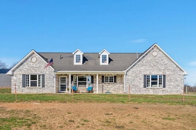 new england style home featuring a front yard and brick siding