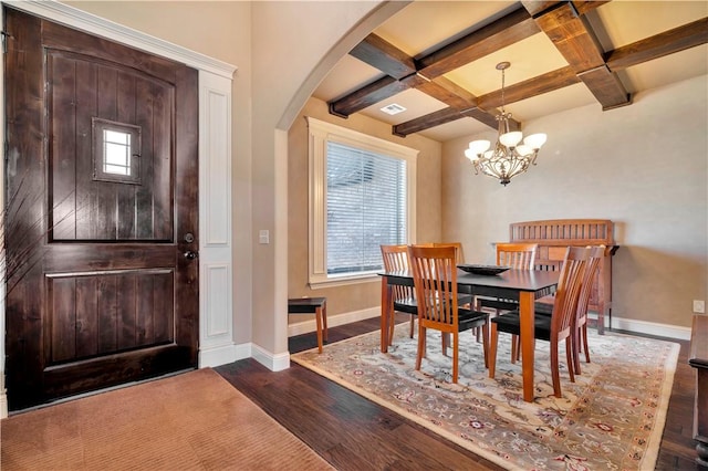 dining room with beam ceiling, dark hardwood / wood-style flooring, an inviting chandelier, and coffered ceiling