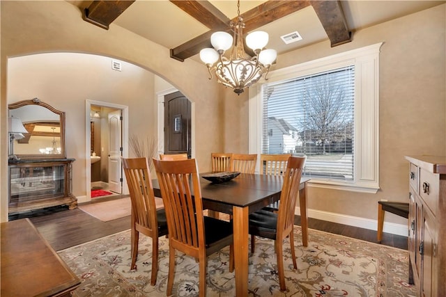 dining space with beamed ceiling, dark hardwood / wood-style floors, and a chandelier