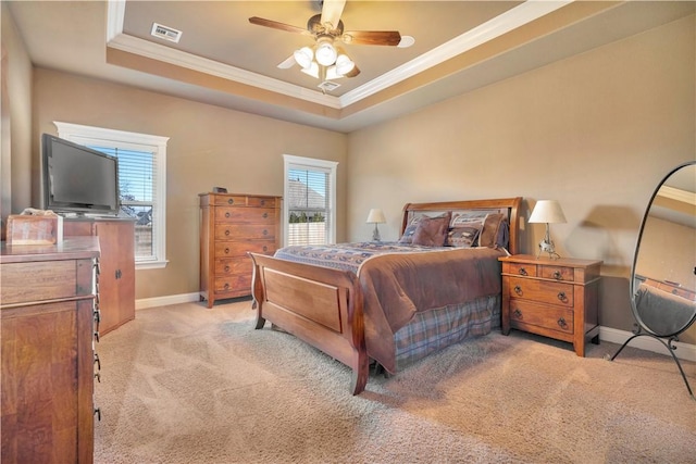 carpeted bedroom with multiple windows, a tray ceiling, ceiling fan, and ornamental molding