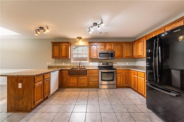 kitchen featuring kitchen peninsula, appliances with stainless steel finishes, light tile patterned floors, and sink