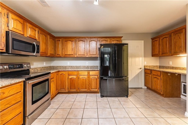 kitchen with light stone counters, appliances with stainless steel finishes, and light tile patterned floors