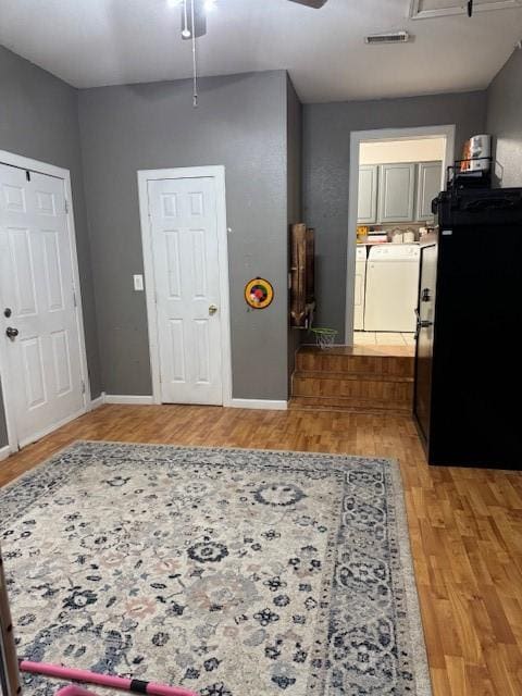 foyer with independent washer and dryer, light hardwood / wood-style flooring, and ceiling fan