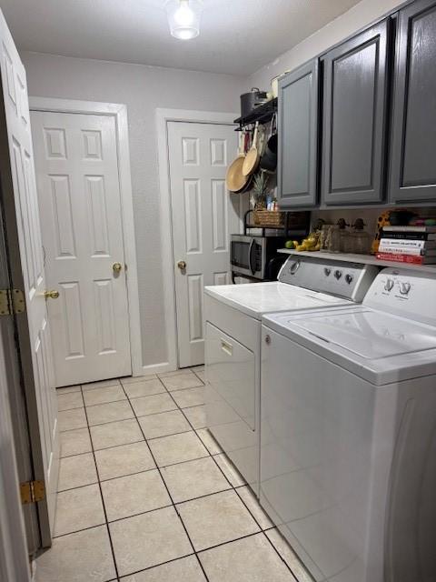 washroom with cabinets, light tile patterned floors, and washing machine and clothes dryer