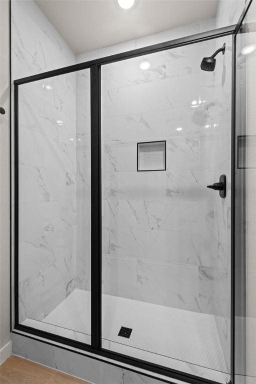 bathroom featuring a shower with shower door and wood-type flooring