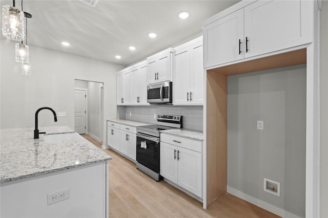 kitchen featuring sink, white cabinets, decorative light fixtures, and appliances with stainless steel finishes