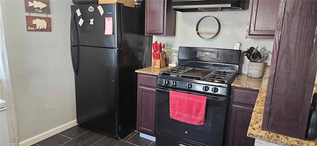 kitchen featuring black appliances, light stone counters, and ventilation hood