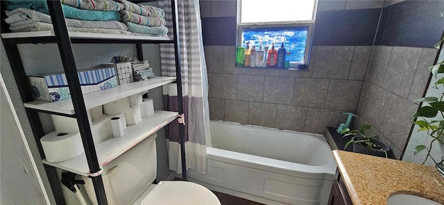 bathroom featuring vanity, tile walls, and toilet