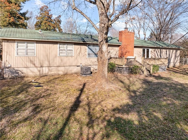 view of side of property featuring a wooden deck, a yard, and central AC unit