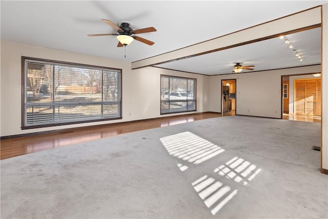 empty room featuring beam ceiling, carpet floors, and ceiling fan