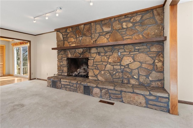 carpeted living room with a fireplace, rail lighting, and crown molding