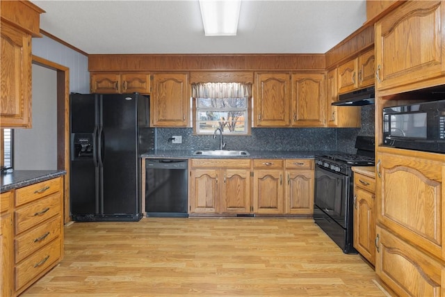 kitchen with black appliances, decorative backsplash, sink, and light hardwood / wood-style flooring