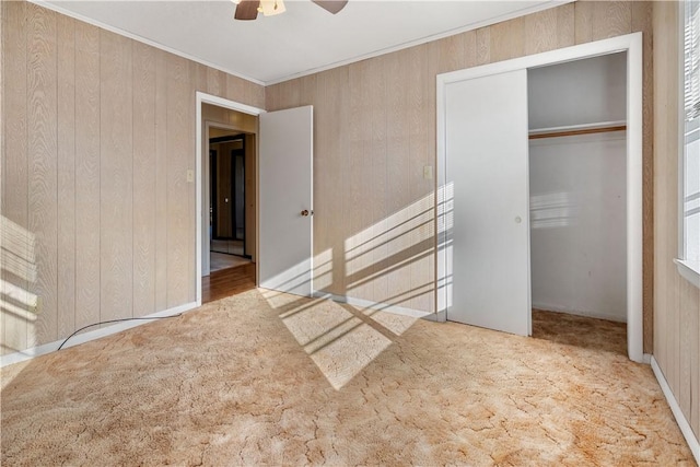 unfurnished bedroom featuring ceiling fan, wooden walls, and a closet