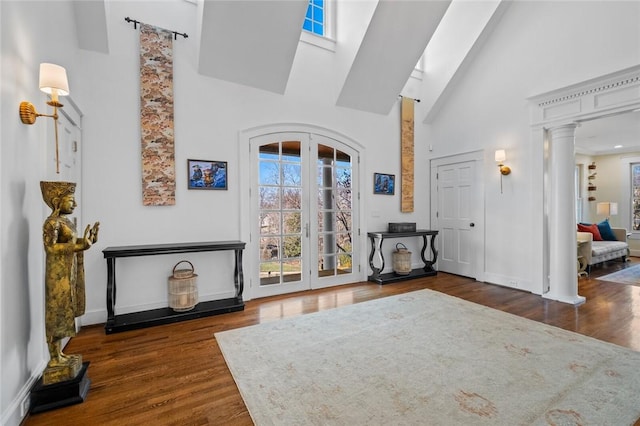 foyer entrance featuring a towering ceiling, dark hardwood / wood-style floors, and ornate columns