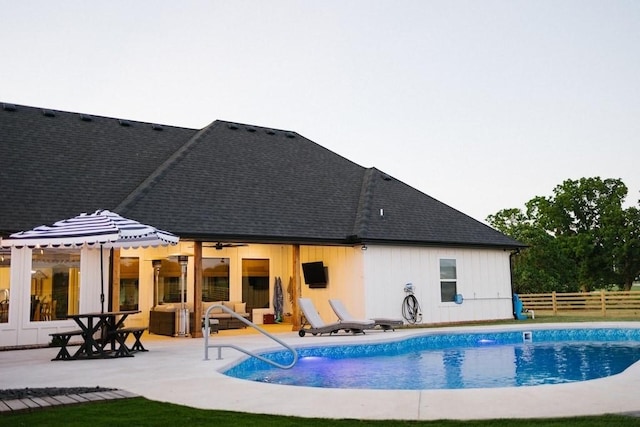 back of property with an outdoor living space, a patio area, and a fenced in pool