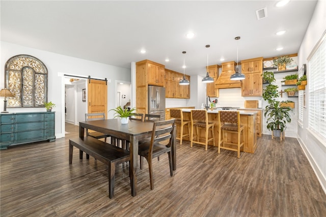 dining space featuring plenty of natural light, dark hardwood / wood-style floors, and a barn door