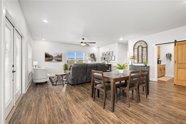 dining area featuring ceiling fan, dark hardwood / wood-style flooring, and a barn door