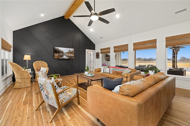 living room with ceiling fan, light wood-type flooring, beamed ceiling, and high vaulted ceiling