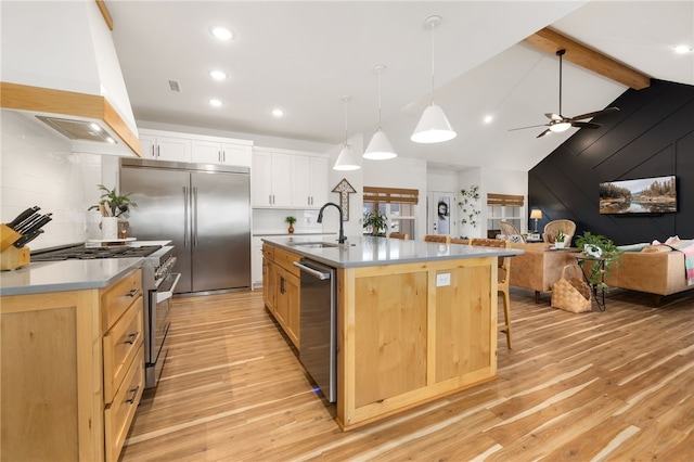 kitchen featuring premium range hood, white cabinetry, a kitchen island with sink, high end appliances, and sink