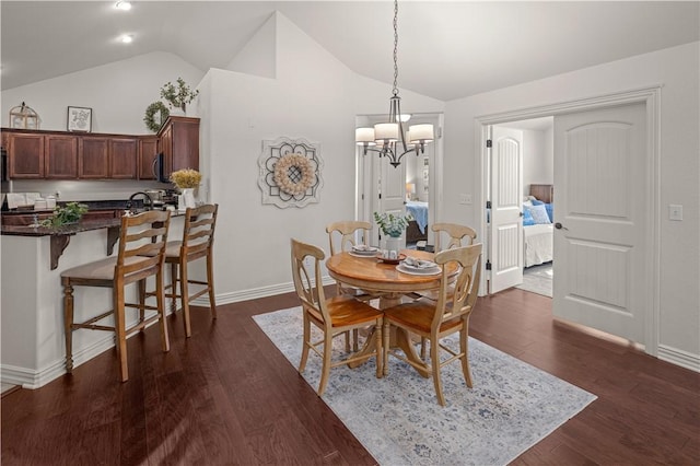 dining space featuring dark hardwood / wood-style floors, lofted ceiling, and an inviting chandelier