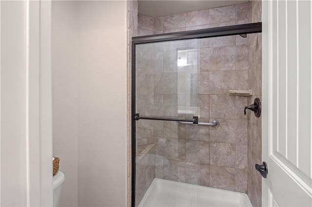 bathroom featuring a shower with door and toilet