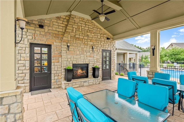 view of patio featuring an outdoor stone fireplace and ceiling fan